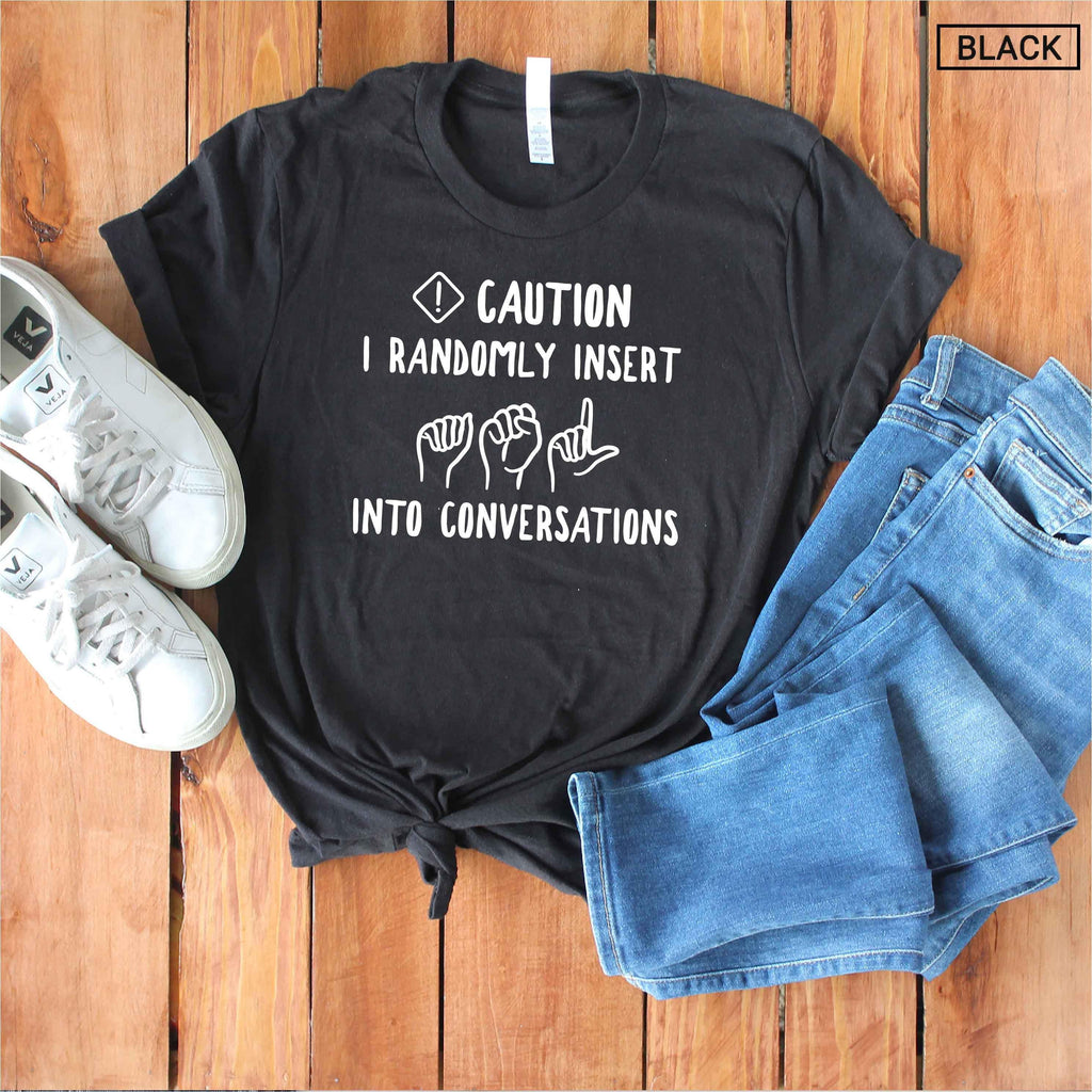 May include: A black short-sleeved t-shirt featuring white text that reads CAUTION I RANDOMLY INSERT ASL INTO CONVERSATIONS, accompanied by white line-art illustrations of three hand signs representing the letters A, S, and L.